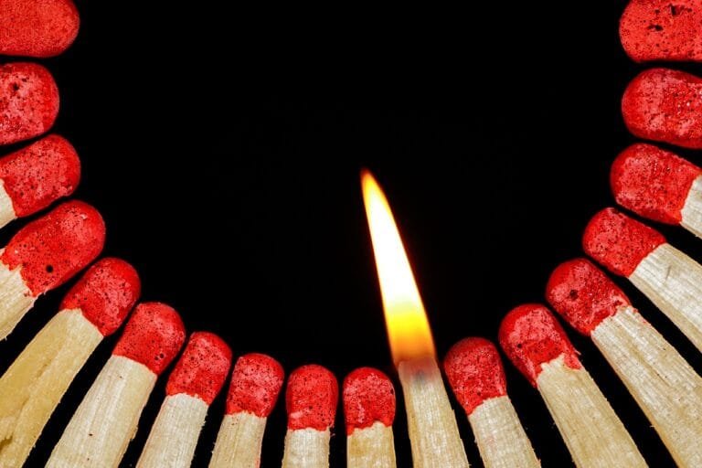 A burning matchstick surrounded by unlit matches, symbolizing a spark of change or ignition of ideas in Manipur.