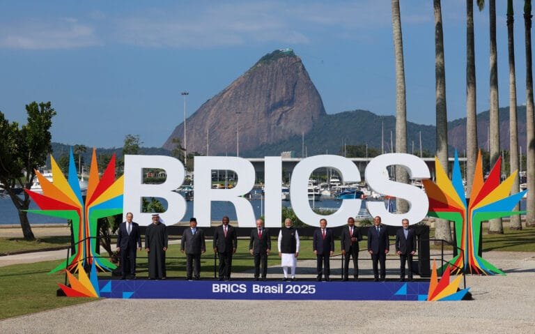 "Leaders of BRICS nations posing at the BRICS Summit 2025 in Brasil, with large BRICS letters and Sugarloaf Mountain in the background, symbolizing global cooperation and multilateralism."